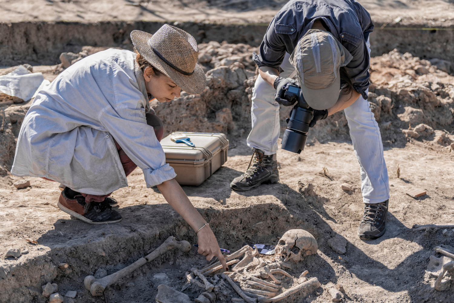 Archeologický výzkum, dvě osoby se sklání v prostoru vykopávky